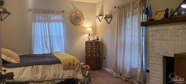 carpeted bedroom featuring multiple windows, a brick fireplace, and baseboards