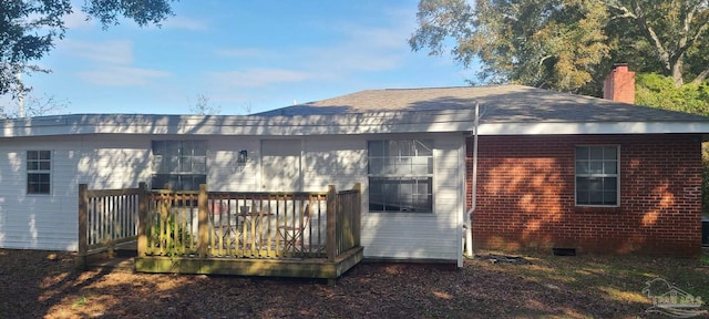 rear view of property with a deck, brick siding, and a chimney