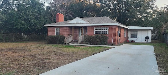 bungalow with brick siding, a chimney, a front yard, entry steps, and fence