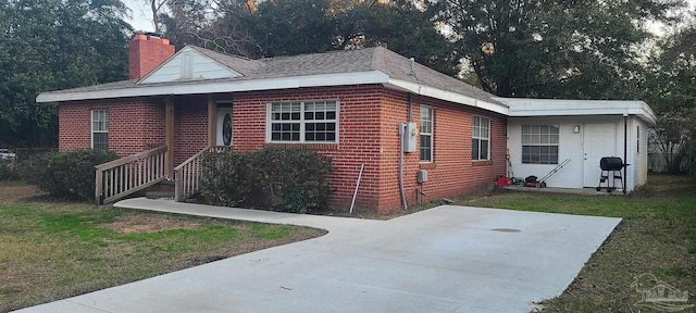 view of front of house featuring brick siding, a chimney, and a front lawn