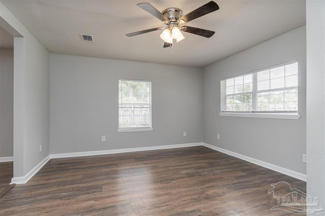 unfurnished room with dark wood-style floors, baseboards, visible vents, and a healthy amount of sunlight