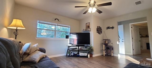 living area with dark wood-type flooring, visible vents, ceiling fan, and baseboards