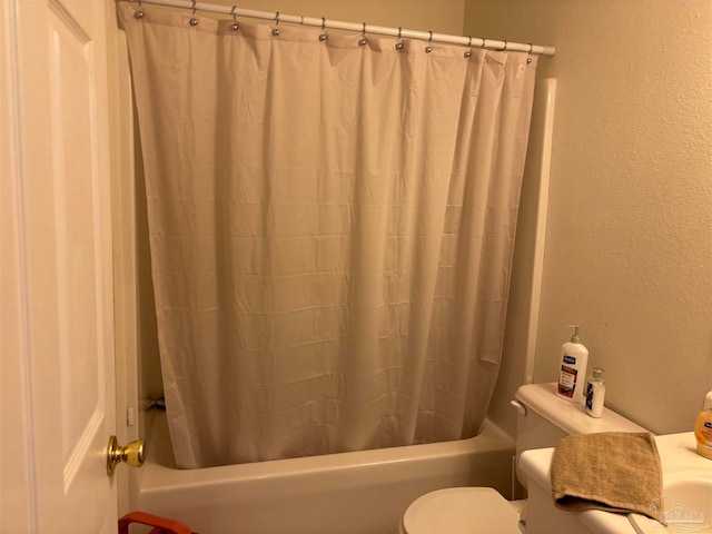 full bathroom with a textured wall, toilet, and shower / bath combo with shower curtain