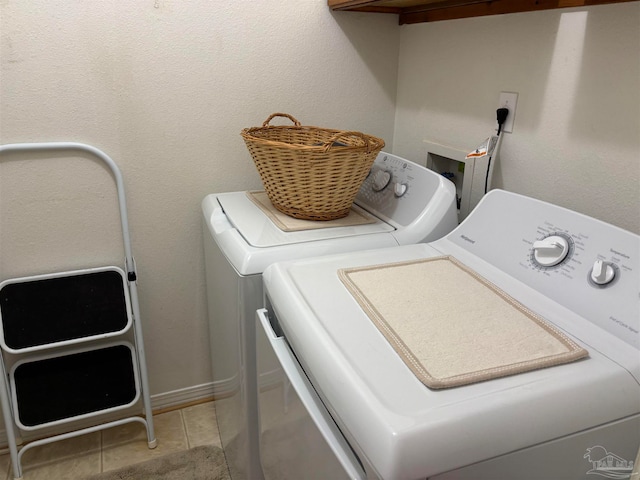 clothes washing area with washer and clothes dryer and light tile patterned floors