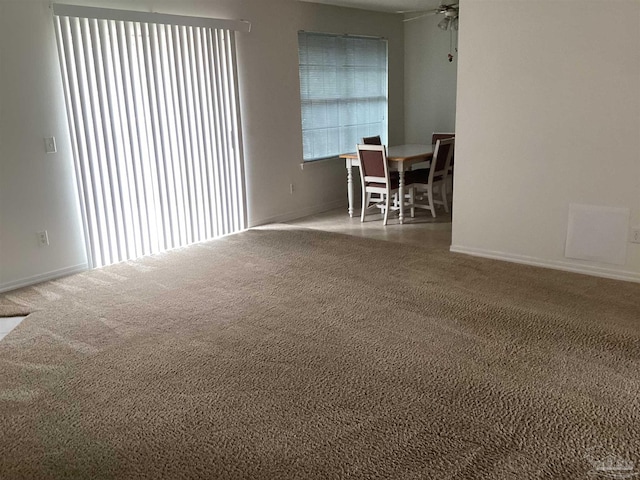 spare room with carpet floors, a ceiling fan, and baseboards