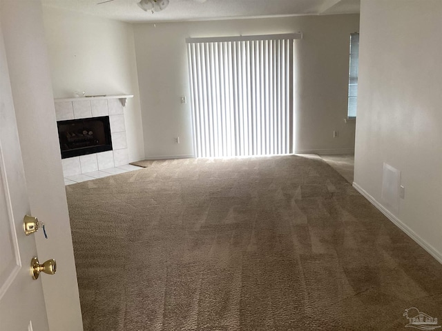 unfurnished living room featuring baseboards, a ceiling fan, carpet flooring, and a tile fireplace