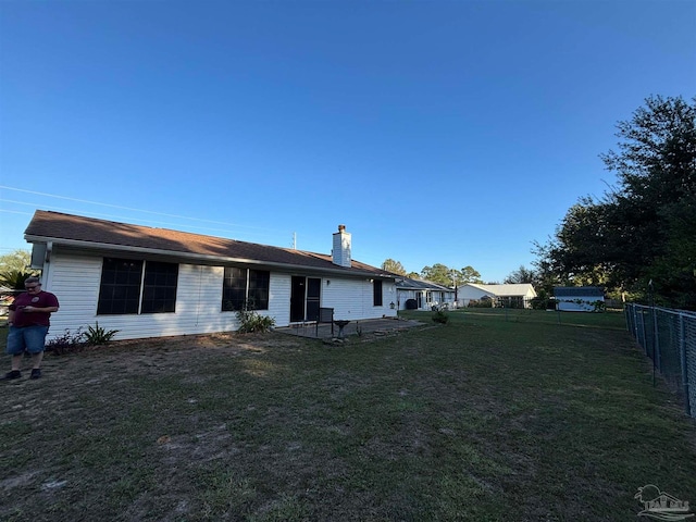 exterior space with a patio, a lawn, a chimney, and fence