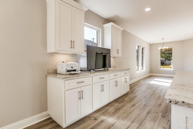 kitchen featuring an inviting chandelier, light stone countertops, decorative light fixtures, light hardwood / wood-style floors, and white cabinetry