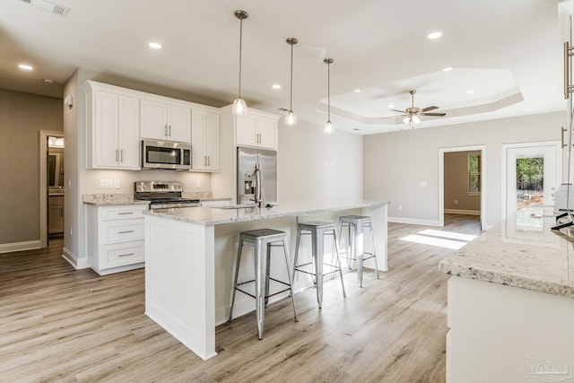 kitchen with white cabinetry, a center island with sink, hanging light fixtures, and appliances with stainless steel finishes