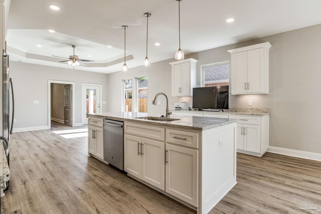 kitchen featuring light stone countertops, ceiling fan, sink, dishwasher, and an island with sink