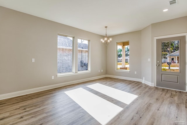 unfurnished dining area with an inviting chandelier and light hardwood / wood-style flooring