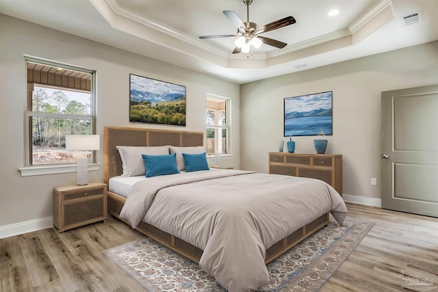 bedroom with ceiling fan, light hardwood / wood-style floors, ornamental molding, and a tray ceiling