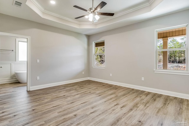 spare room with ceiling fan, light hardwood / wood-style floors, ornamental molding, and a tray ceiling