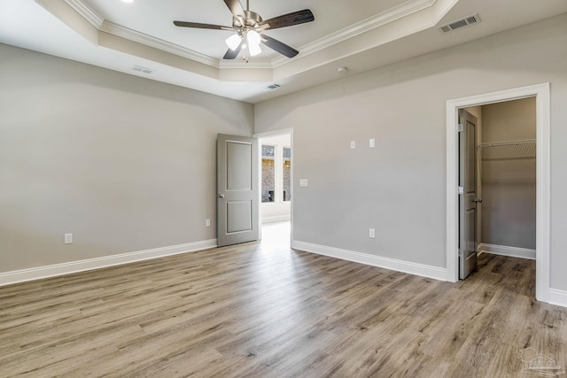 unfurnished room with light hardwood / wood-style floors, a raised ceiling, and ornamental molding