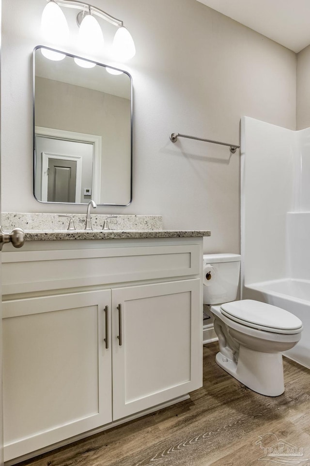 full bathroom featuring wood-type flooring, vanity, bathing tub / shower combination, and toilet