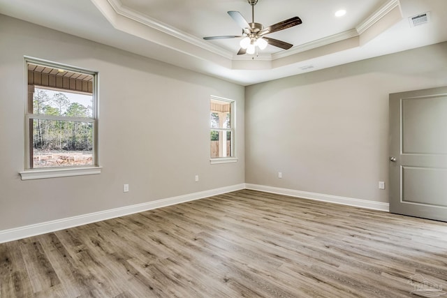 spare room featuring ceiling fan, a raised ceiling, crown molding, and light hardwood / wood-style flooring