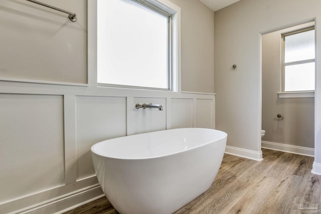 bathroom with hardwood / wood-style flooring, toilet, and a tub