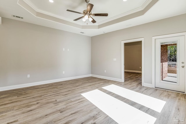 unfurnished room featuring light wood-type flooring, a tray ceiling, ceiling fan, and crown molding