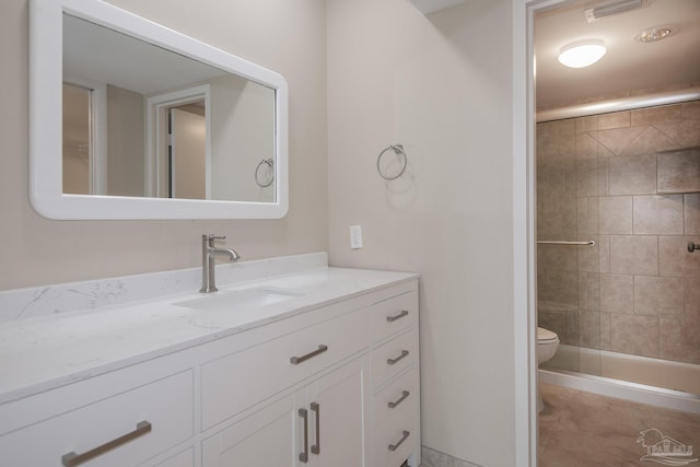 bathroom featuring a tile shower, vanity, and toilet