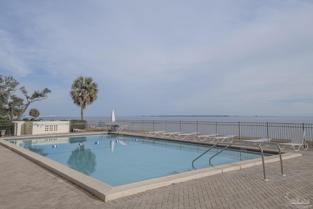 view of swimming pool featuring a patio and a water view