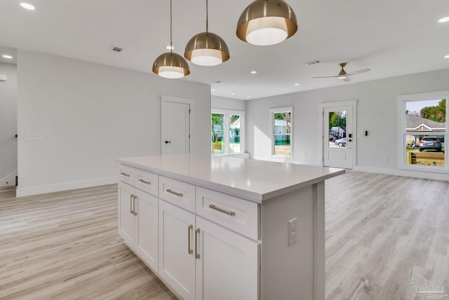 kitchen featuring white cabinetry, hanging light fixtures, a healthy amount of sunlight, and light wood-type flooring