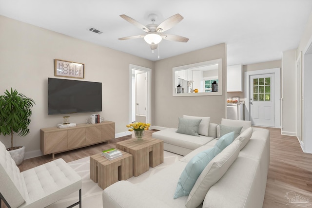 living room with light hardwood / wood-style flooring, independent washer and dryer, and ceiling fan