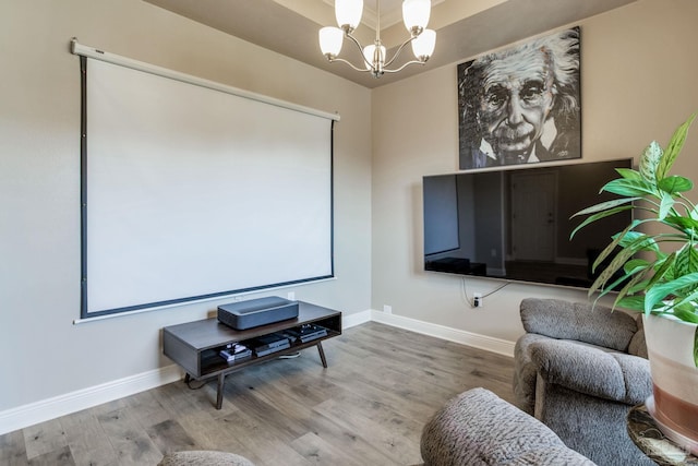 cinema room with baseboards, an inviting chandelier, and wood finished floors