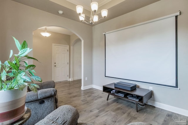 home theater room with baseboards, arched walkways, a chandelier, and wood finished floors