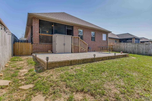 back of house featuring a patio, brick siding, a lawn, and a fenced backyard