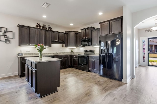 kitchen featuring dark brown cabinetry, black appliances, light wood-style flooring, and a center island