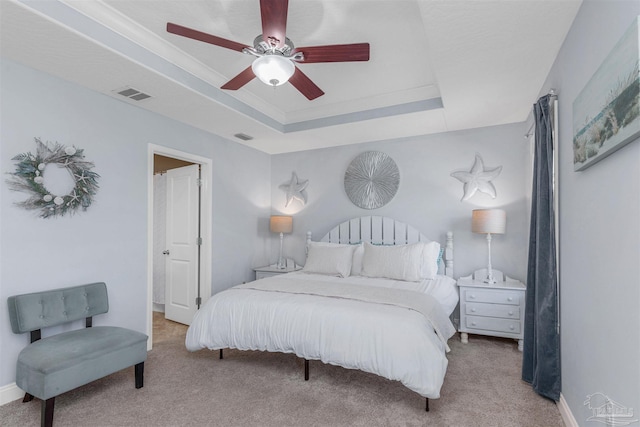 bedroom with ceiling fan, a raised ceiling, and light carpet