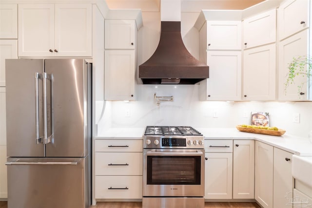 kitchen featuring white cabinetry, appliances with stainless steel finishes, custom range hood, and backsplash