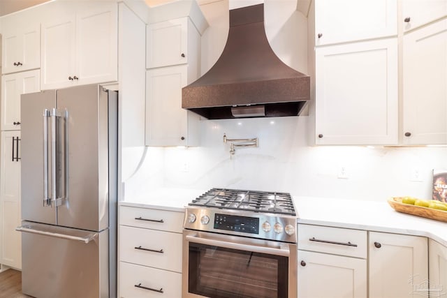 kitchen featuring premium range hood, appliances with stainless steel finishes, tasteful backsplash, and white cabinets