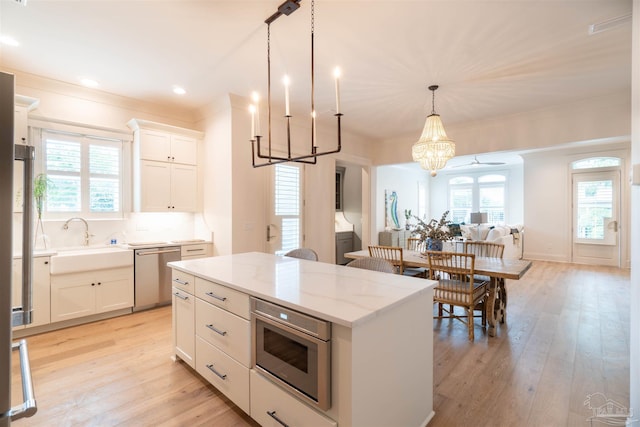 kitchen with decorative light fixtures, sink, white cabinets, a center island, and stainless steel appliances