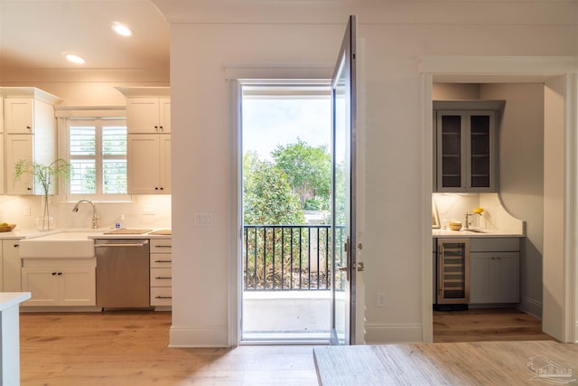 doorway to outside with sink, beverage cooler, and light wood-type flooring