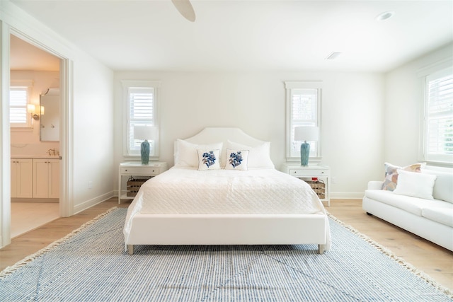 bedroom with ceiling fan, ensuite bathroom, and light hardwood / wood-style floors