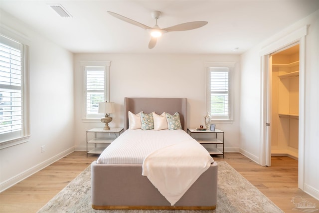 bedroom with a walk in closet, light hardwood / wood-style flooring, and ceiling fan