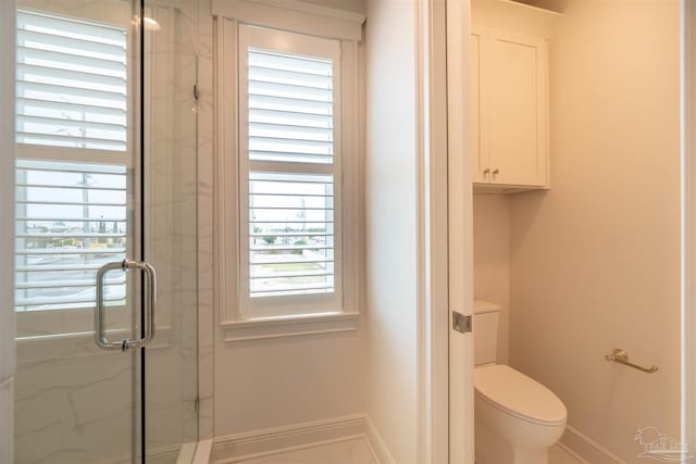 bathroom featuring a shower with shower door and toilet