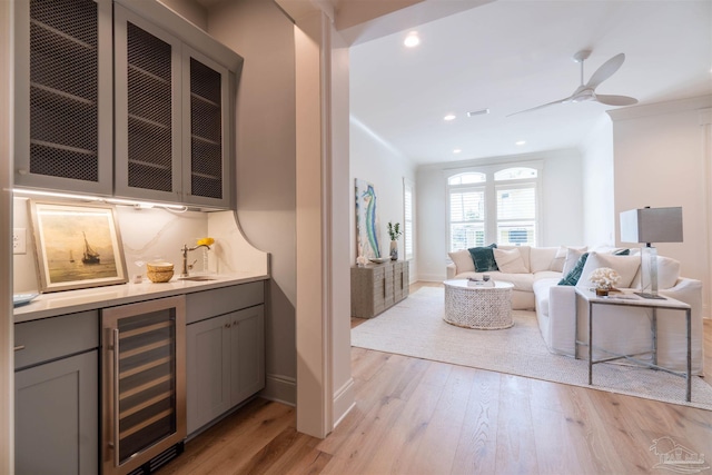 bar featuring crown molding, gray cabinetry, wine cooler, and light wood-type flooring