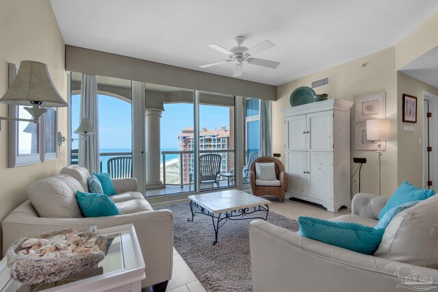 tiled living room with ceiling fan and a water view