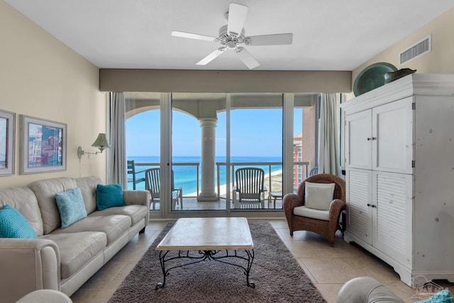 tiled living room featuring ceiling fan and a water view