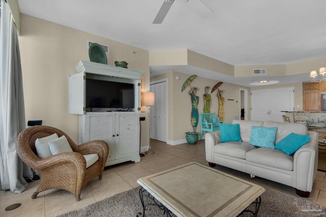 tiled living room featuring ceiling fan with notable chandelier