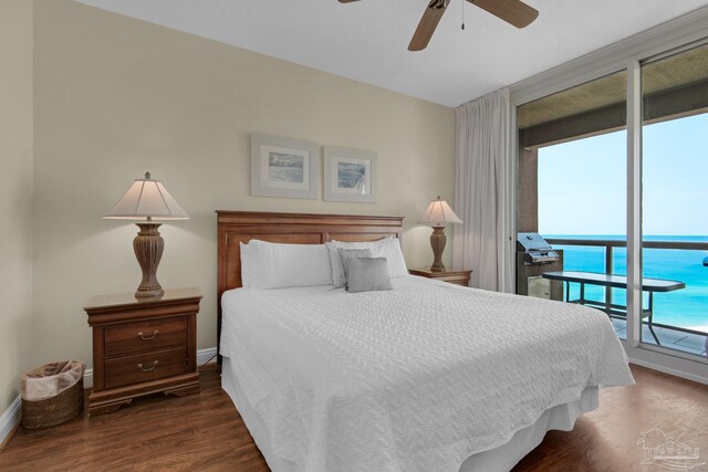 bedroom with ceiling fan, dark hardwood / wood-style floors, access to outside, and a water view