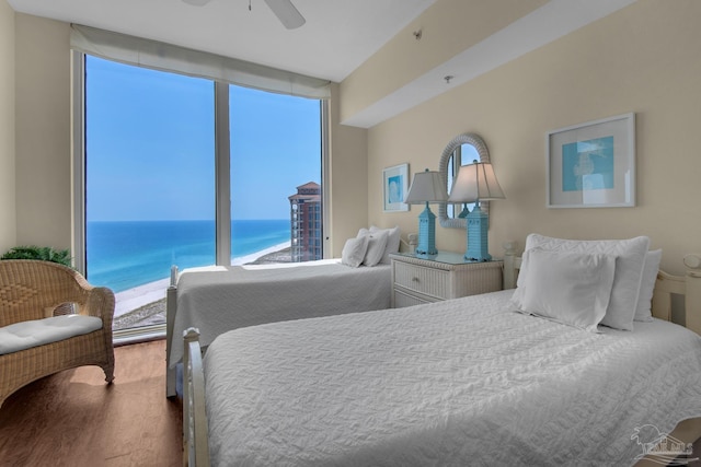 bedroom with ceiling fan, a water view, and wood finished floors