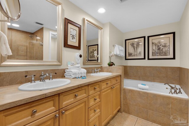 bathroom featuring tiled bath, double sink vanity, and tile patterned flooring