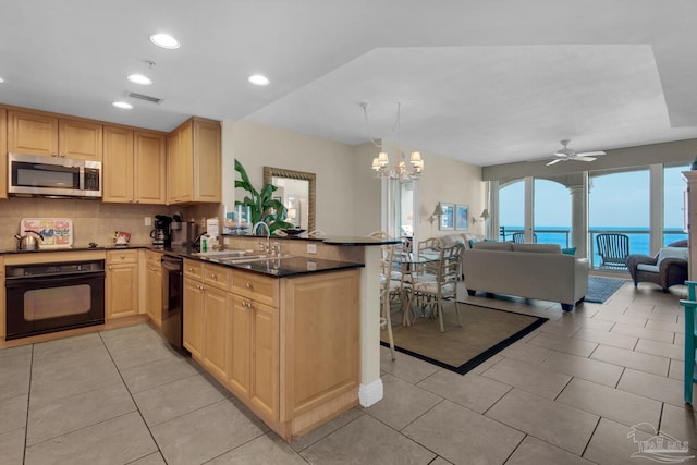 kitchen featuring tasteful backsplash, ceiling fan with notable chandelier, kitchen peninsula, black appliances, and a water view