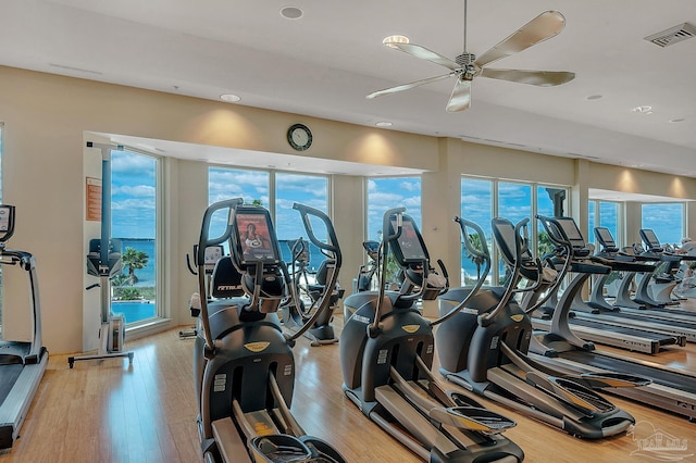 exercise room with light wood-type flooring, visible vents, and ceiling fan