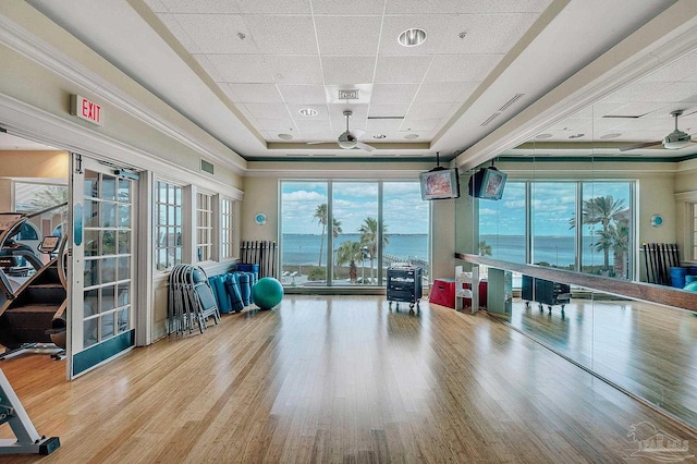 interior space with ceiling fan, visible vents, a tray ceiling, and wood finished floors