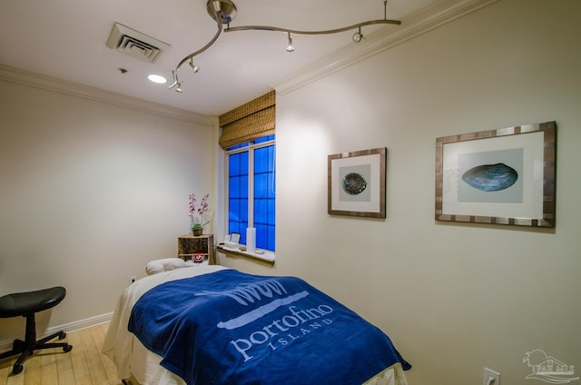 bedroom with baseboards, wood finished floors, visible vents, and crown molding