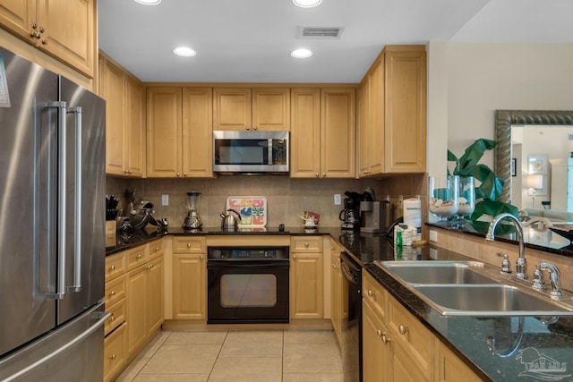 kitchen with decorative backsplash, appliances with stainless steel finishes, light tile patterned floors, sink, and dark stone countertops